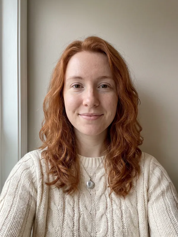 AI-generated portrait of Mia, a fictional woman with wavy copper-red hair, a cream sweater and a silver locket
